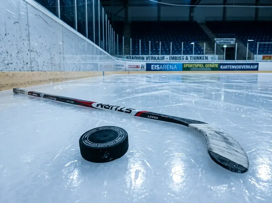 Eishockeyschläger und Puck auf einer Eisfläche in einer Arena